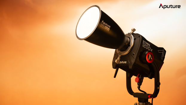 Aputure spotlight mounted on a stand against a warm amber-toned backdrop.