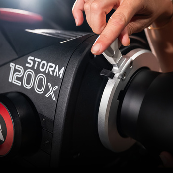 Hand adjusting the focus ring on a Storm 1200X camera lens during setup.