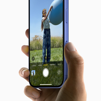 Smartphone held in hand displaying a portrait photo of a person in a field with a large white sphere overhead, camera interface visible on screen.