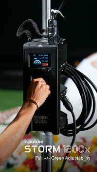 Hand adjusting controls on a portable lighting unit with coiled cable attached.