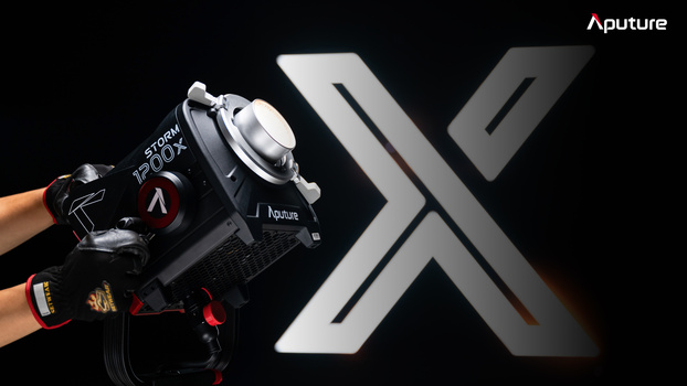Hands holding an Aputure light modifier with a large X-shaped graphic displayed against a black background.
