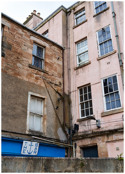 Weathered multi-story residential building with contrasting stone and rendered facades, narrow alley composition.