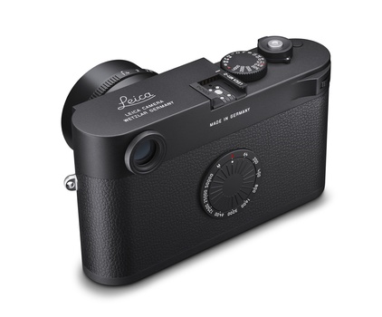 Black rangefinder camera with manual focus and exposure controls, shown from above at three-quarter angle.
