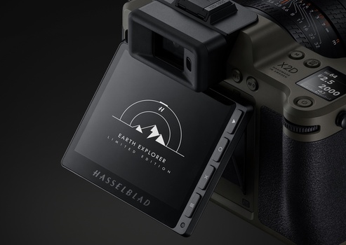 Hasselblad digital camera back with leather strap displayed next to professional camera body against dark background.