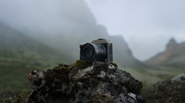 Digital camera mounted on a moss-covered rock overlooking a misty mountain valley.