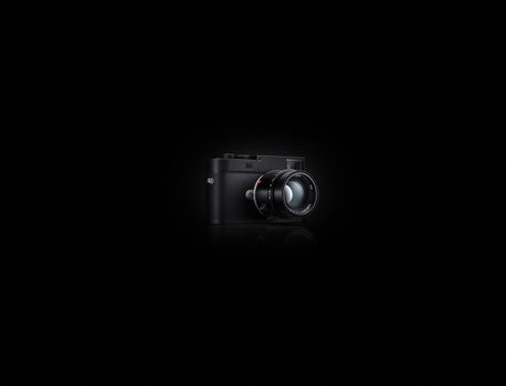Black digital camera with standard lens against dark background.