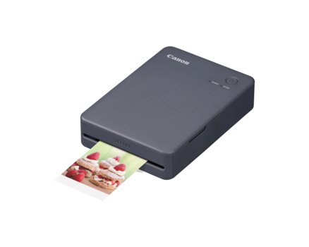 Canon compact photo printer with a color photo ejecting from the output slot.