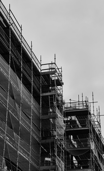 Multistory building under construction with metal scaffolding covering the facade.