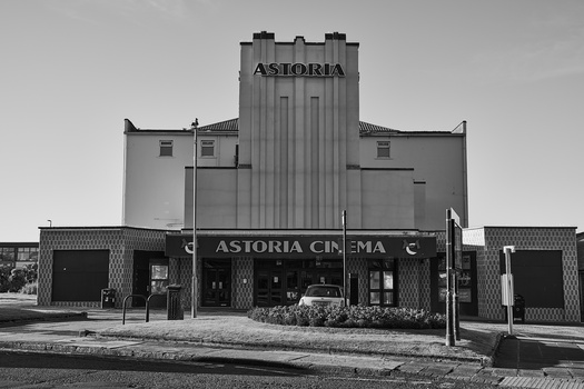 Art Deco cinema facade with vertical tower element and marquee in black and white.