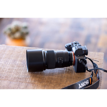 Sony camera with telephoto lens on wooden surface with blurred cityscape background.