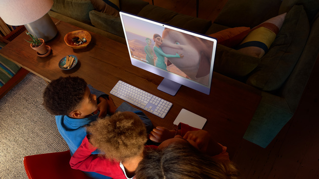 Young child viewing video content on a desktop monitor in a home office setting.