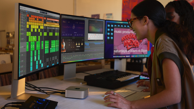 Music producer working at a multi-monitor setup displaying digital audio workstation software and production tools.