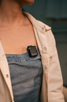 Person wearing beige overshirt over denim top with smartwatch visible on wrist.