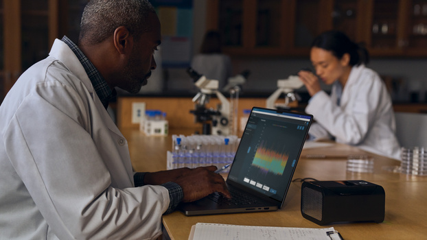 Photographer reviewing thermal or scientific imaging data on a laptop in a laboratory setting.