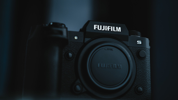 Fujifilm S mirrorless camera body shown from front angle against dark blue background.