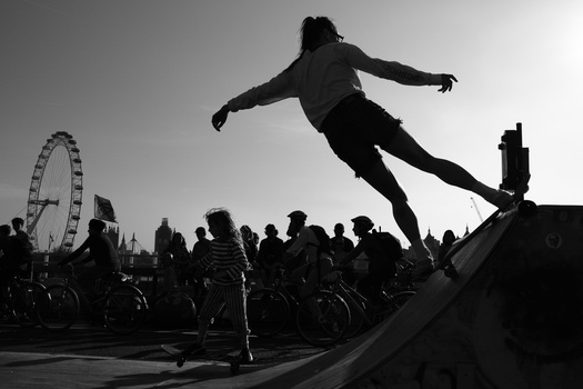 Skateboarder launching into the air off a ramp with a crowd and ferris wheel in the background.