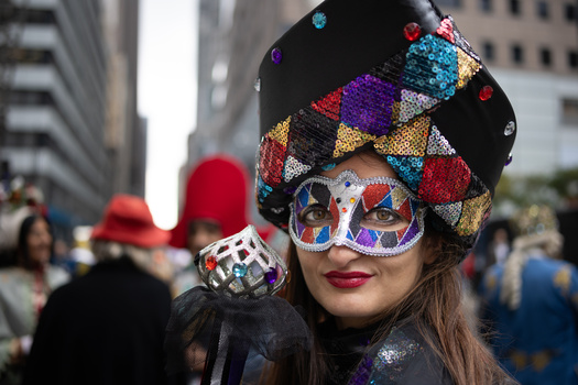 Person wearing colorful argyle beanie and sequined sunglasses at outdoor urban event.