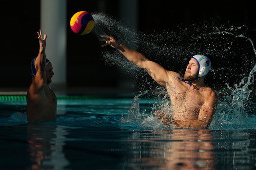 Water polo player throwing ball while in pool during match.