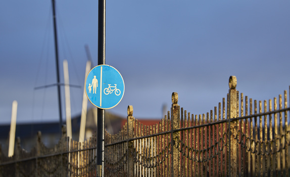 Blue circular sign mounted on black pole showing pedestrian and bicycle symbols with divided sections.