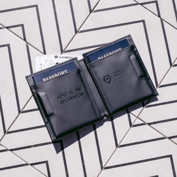 Two open black leather passport wallets displayed on a geometric patterned background.