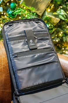 Open camera bag with multiple compartments and organizers displayed against a blurred outdoor background.
