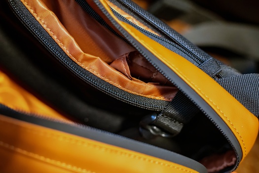 Close-up of an open zipper on a yellow and black bag with brown leather interior visible.