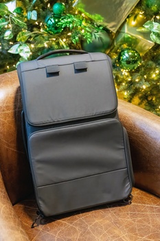 Gray and black camera backpack displayed on a wooden surface with a decorated Christmas tree in the background.