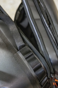Close-up of black camera bag straps and zipper details showing texture and construction.