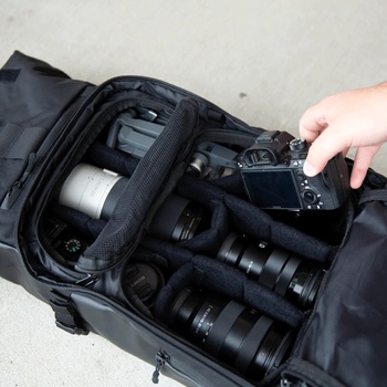 Camera bag organizer displaying a mirrorless camera and collection of interchangeable lenses arranged in padded compartments.