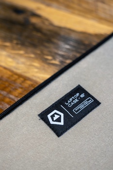 Black product label or tag on gray fabric with wooden surface in background.