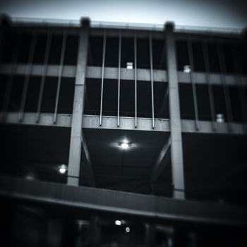 Black and white photograph of a modernist building facade with vertical ribbed columns and illuminated windows at night.