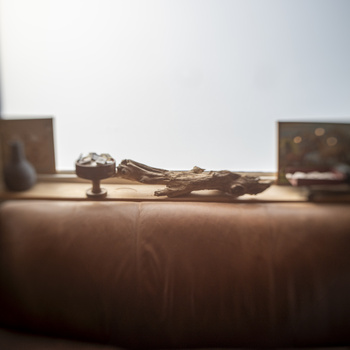 Reclined wooden figure on a draped surface with blurred objects and bright backlighting.