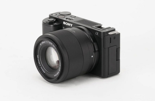 Sony Alpha mirrorless camera with attached prime lens on white background.