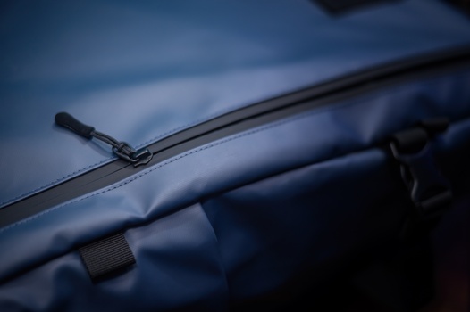 Close-up of a car windshield wiper blade against a blue vehicle hood and sky.