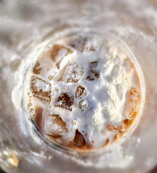 Macro photograph of a water droplet with suspended particles and debris captured in sharp detail.
