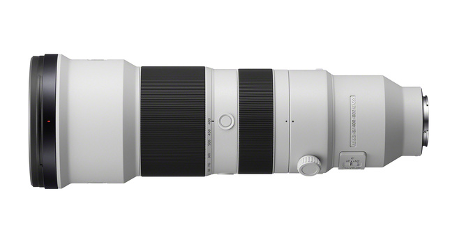 Side view of a white and black telephoto zoom lens with ribbed focus ring and control elements.