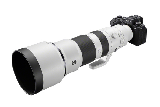 Sony mirrorless camera mounted on a white and black telephoto lens against a white background.