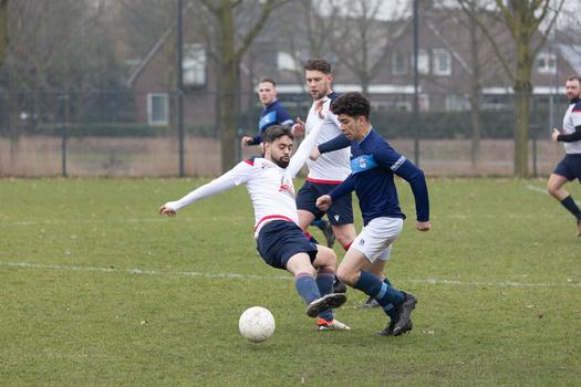 Young soccer players competing for the ball during a youth match on a grass field.