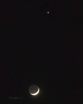 Crescent moon against a dark night sky with a bright star visible above.