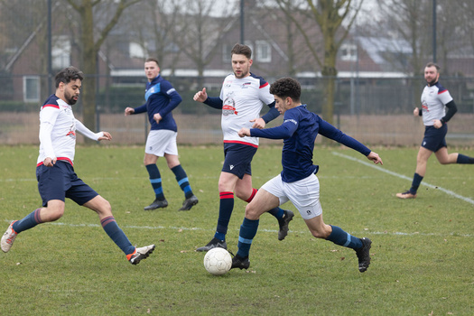 Youth soccer players compete for the ball during a match on a grass field.