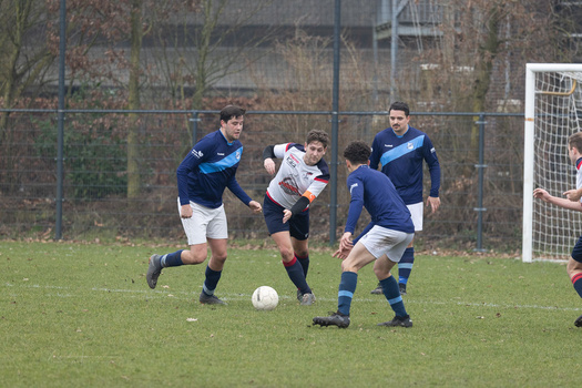Youth soccer players in dark blue and white jerseys competing for the ball during a match on grass field.