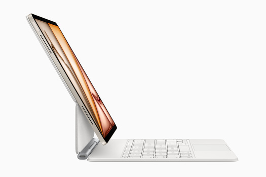 Modern tablet device propped on a stand next to a wireless keyboard in white and silver tones.