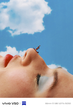 Person's face in profile against blue sky with a small airplane figure balanced on their nose.