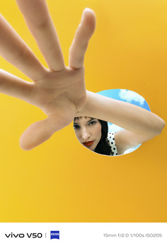Woman's face framed by hands creating a circular composition against bright yellow background.