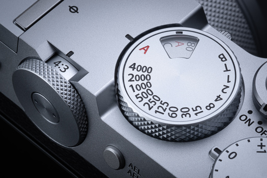 Close-up of a vintage camera's exposure compensation dial showing ISO values and aperture settings.