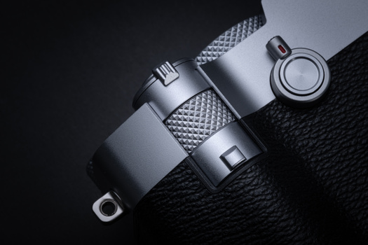 Three silver camera lenses arranged on black textured fabric with studio lighting.