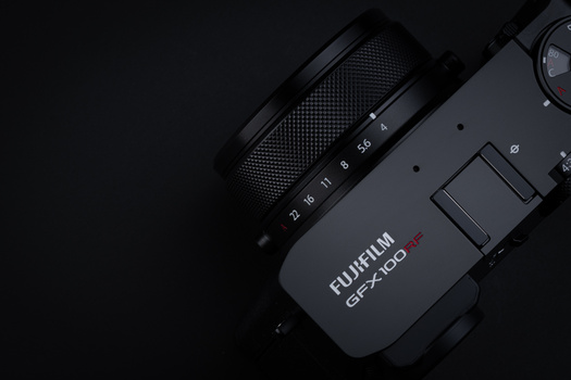 Fujifilm GFX100 medium format camera with attached zoom lens on dark background.