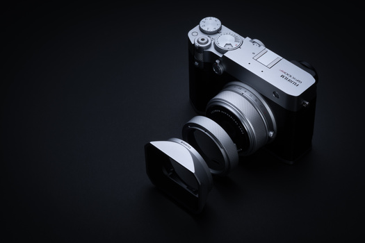 Rangefinder camera with detached lens elements displayed against dark background.