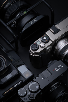 Collection of professional cameras and lenses arranged on a dark surface, showing detailed control dials and optics.