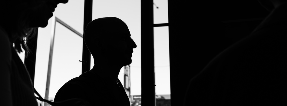 Silhouette of a person in profile facing right, backlit by bright windows creating a high-contrast black and white composition.